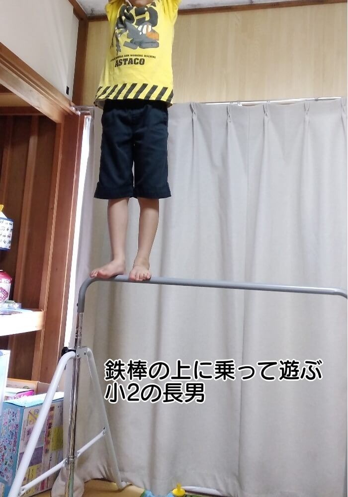 鉄棒の上に乗って遊ぶ小2男児